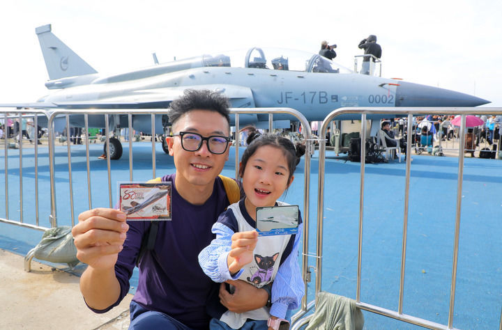 9月19日至23日，2025年长春航空展在长春国际航空博览城举办，吸引诸多参观者观展。图为一对父女在展会现场用航空文创产品卡游致胜空天中国战机卡牌打卡中国战机。新华社记者 许畅 摄